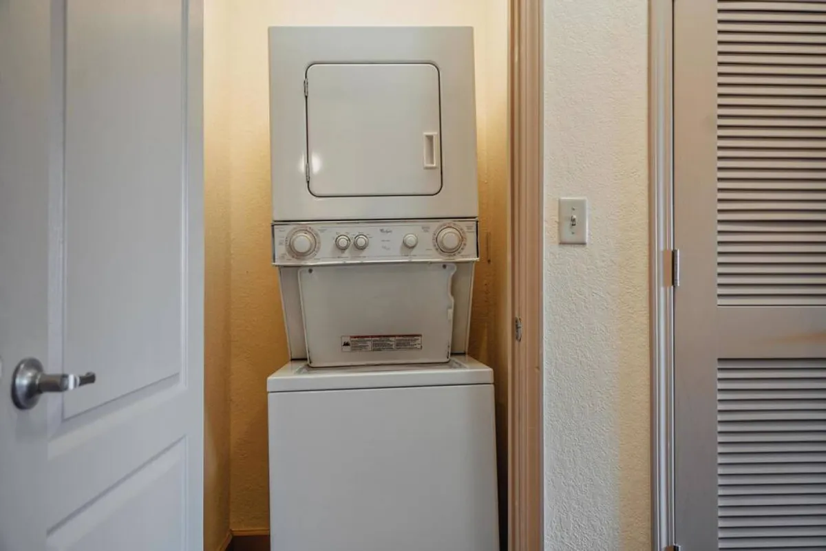Functional laundry area with a stackable washer and dryer unit, providing guests the convenience of fresh linens and easy laundry access during their stay.