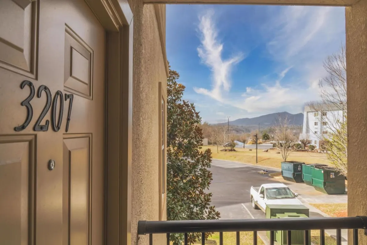 This exterior shot features the entrance of condo unit 3207, with sweeping views of the surrounding mountains and landscape under a clear sky. The setting conveys a sense of arrival and the central location within the region's vibrant entertainment district.