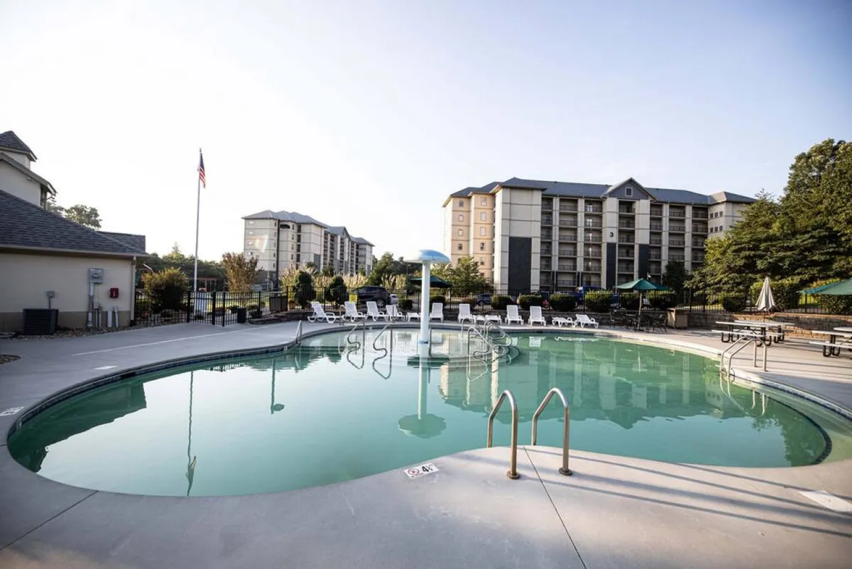 This exterior image showcases a sparkling swimming pool surrounded by lounge chairs, with tall buildings and a flagpole in the background. The atmosphere is lively and inviting, suggesting a perfect spot for families to swim, relax, and socialize outdoors.